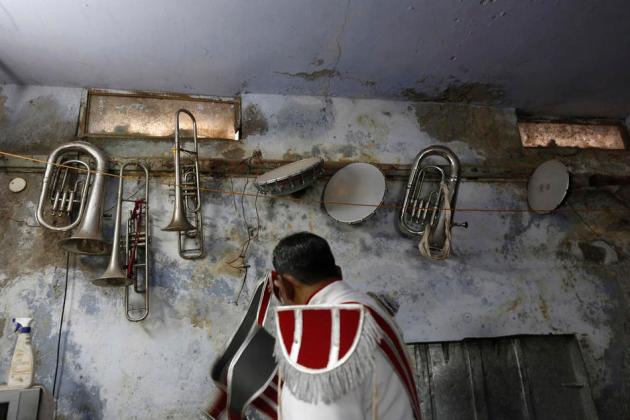 Musical instruments hang on the wall of a basement as a member of a brass band gets ready to perform at the wedding procession in New Delhi
